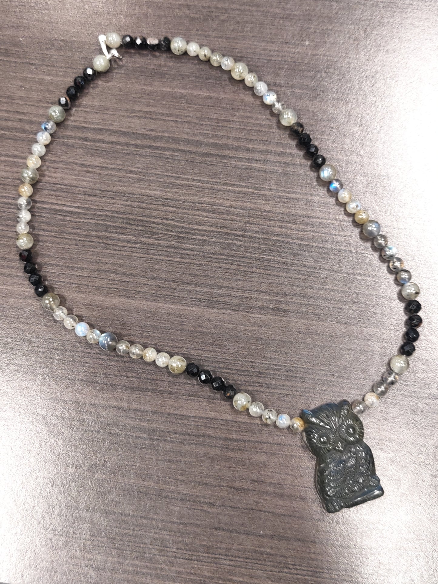 Necklace with owl pendant on a metallic surface