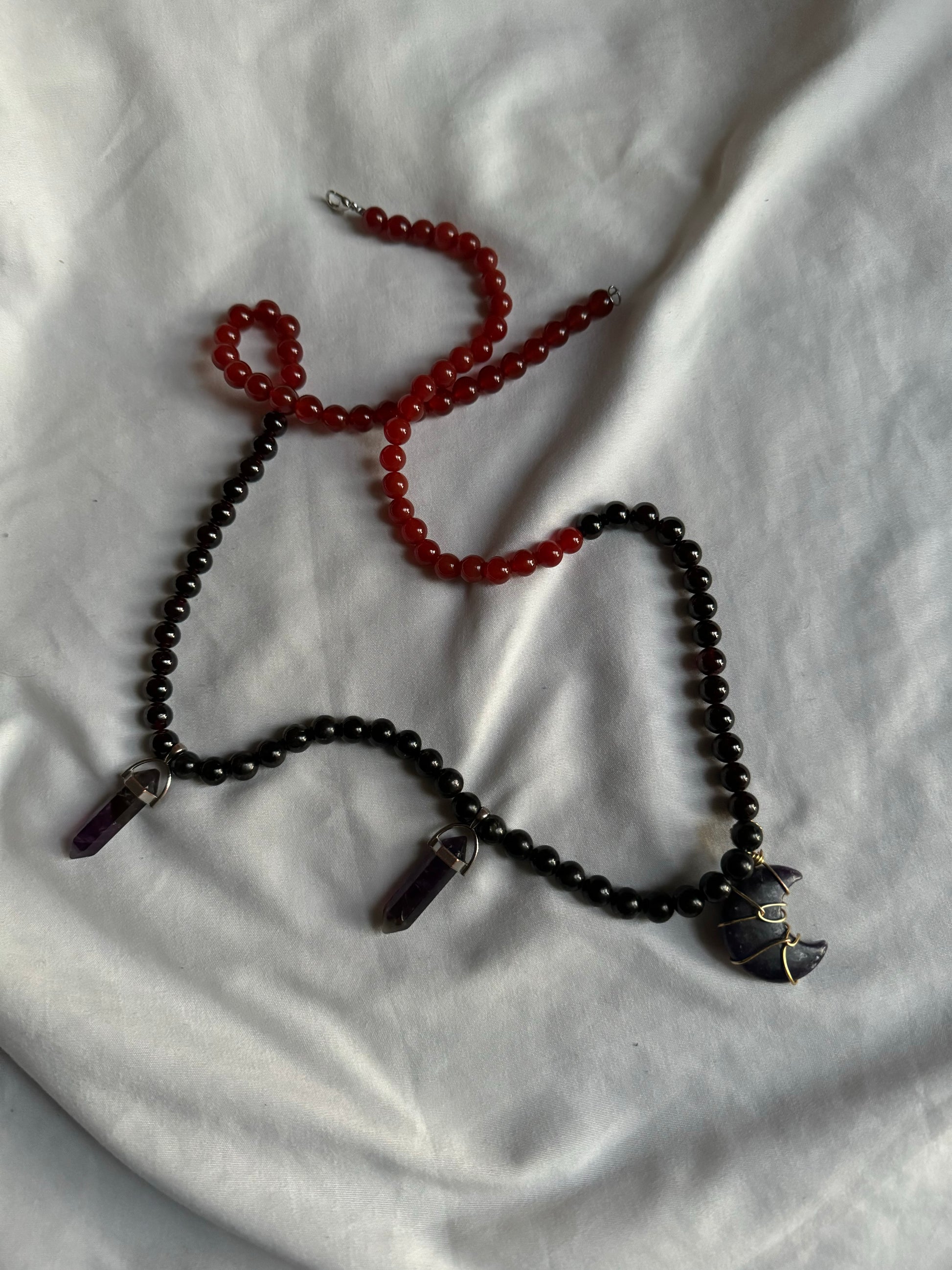 Black and red beaded necklace on a white fabric background