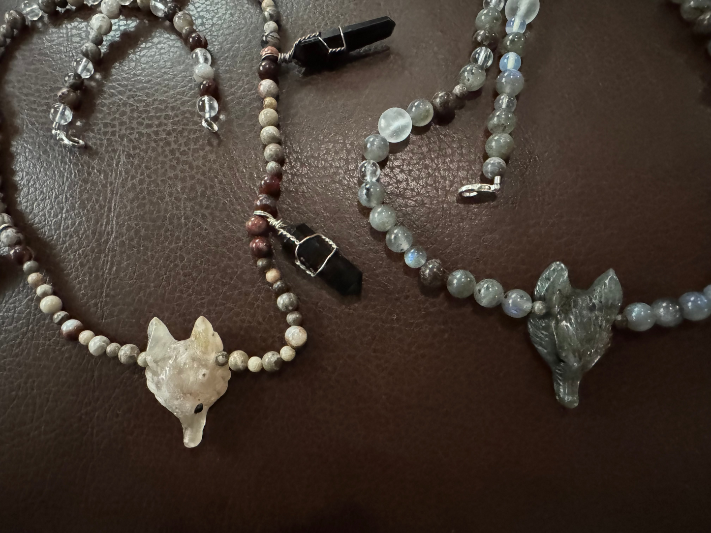 Two beaded necklaces with wolf pendants on a brown surface