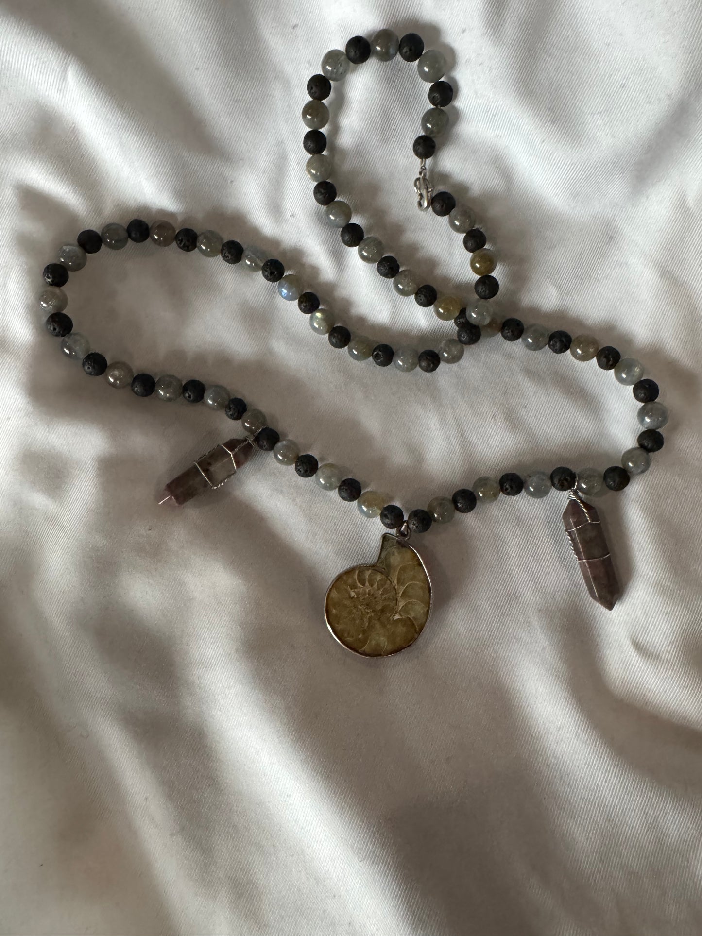 Necklace with beads and a pendant on a white fabric background