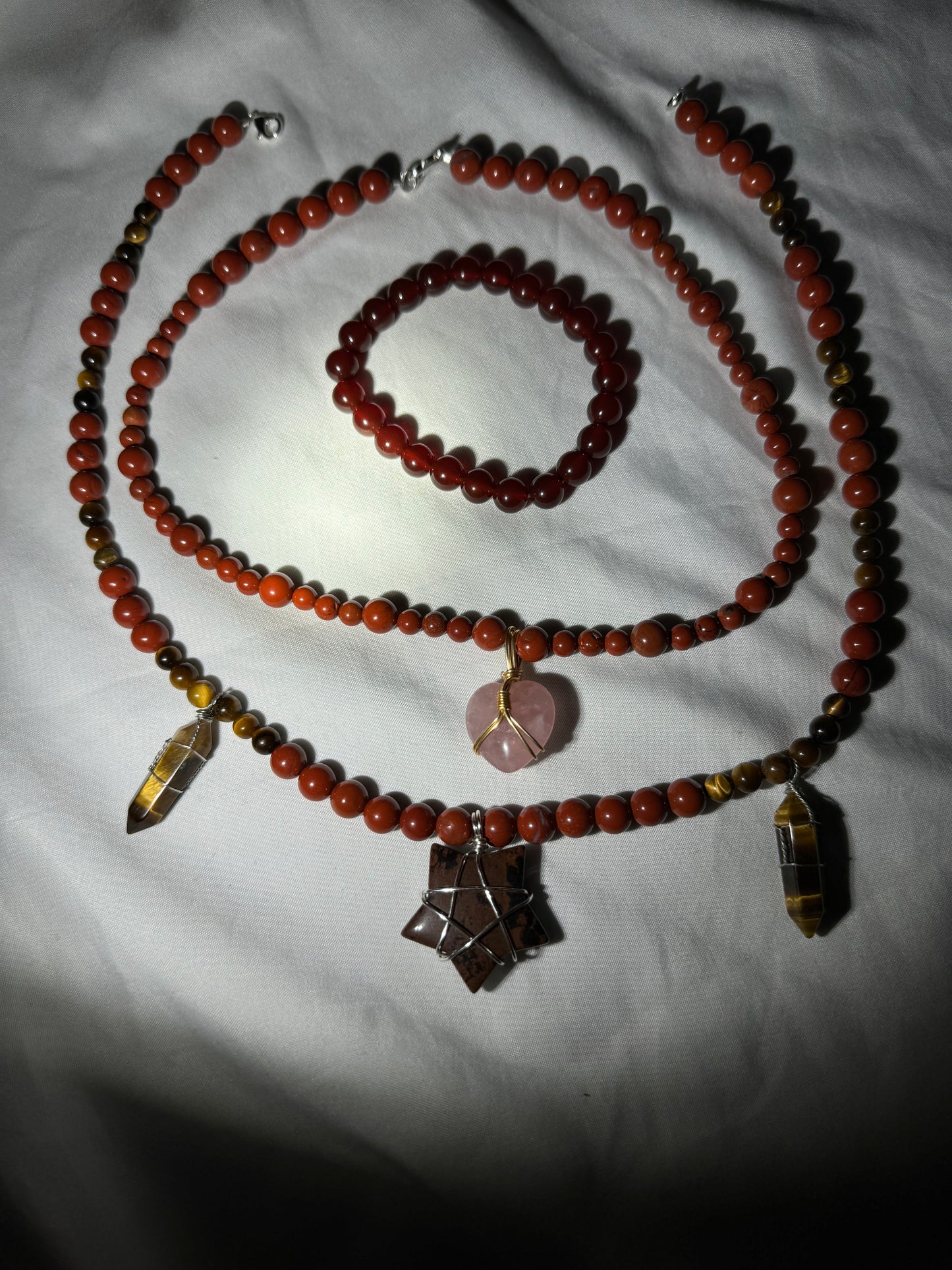 Beaded necklace and bracelet set on a white fabric background