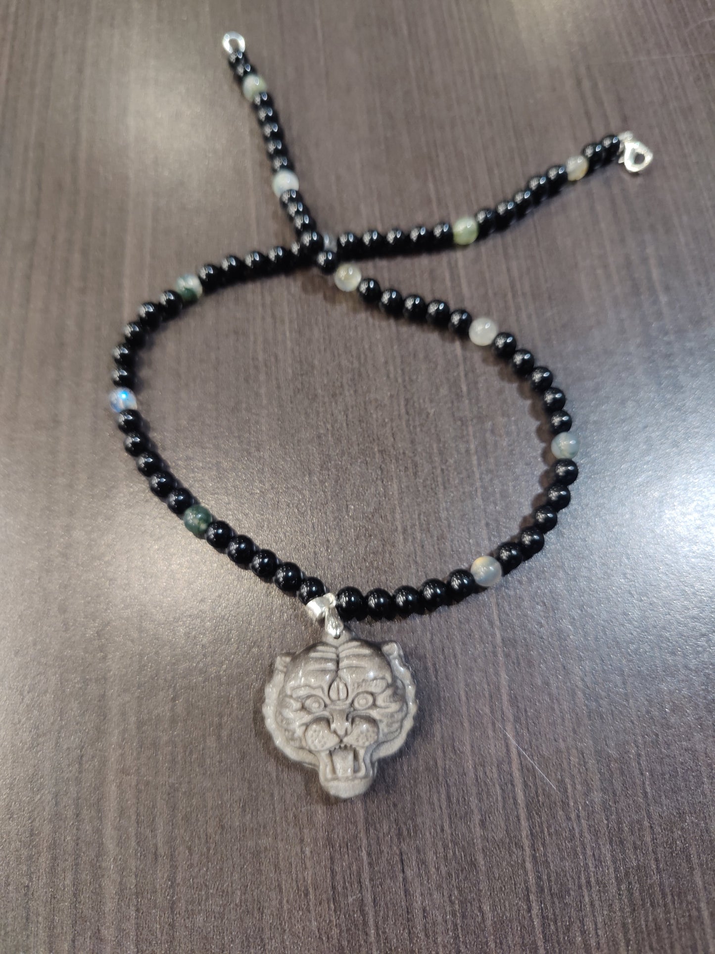 Black beaded bracelet with a silver clasp on a wooden surface